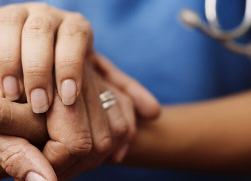 Photo of a nurse holding a patient's hand