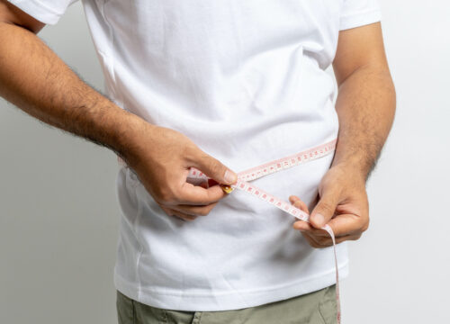 Photo of a man measuring his waistline
