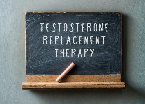 Photo of a small blackboard and chalk. 'Testosterone replacement therapy' is written on the chalkboard.